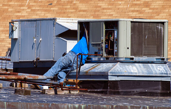 Industrial hvc  heating and air-conditioning repair man fixing a rooftop ac unit in the city