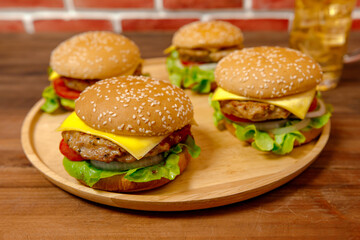 Set of pork burgers on wooden tray in front of brick wall
