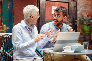 An elderly woman has an interesting talk with her young male friend while spending free time at bar's garden together. Leisure, bar, friendship, outdoor