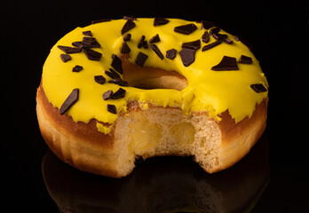 Sweet donut with icing and chocolate drops, isolated on background. A fresh, sweet, round on a black . Stuffed inside. High quality photo