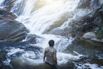 A man looking at pure tropical waterfall.