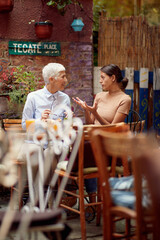 An older woman carefully listen to her young female friend story while they have a drink in the bar. Leisure, bar, friendship, outdoor