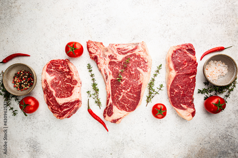 Wall mural variety of fresh raw black angus prime meat steaks t-bone, new york, ribeye and seasoning on white b