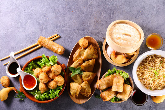 assorted of asian dishes- samosa, fried noodles, spring roll