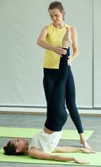 Good shape female Yoga master helps the newcomer student to practice basic gesture and correct to...