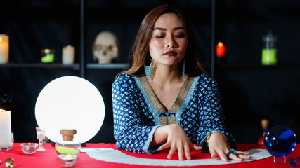 Asian fortune teller reading cards with closed eyes