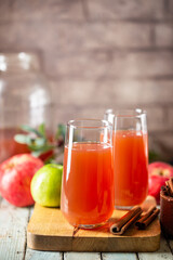 Glass of fresh apple juice and red apples on wooden background