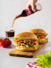 Hamburger, tomatoes, pour a drink of cola on a light background.