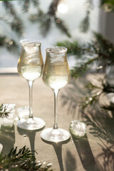 Two glasses on a beautiful vertical postcard with a festive drink surrounded by fir branches