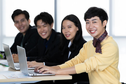 A group of multi-sex colleagues businesspeople, tomboy and transgender gay, working together with happy and intimate manner with laptop notebook computer in office
