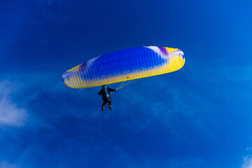 Paragliding in blue sky. Parachute with paraglider is flying. Extreme sports, freedom concept