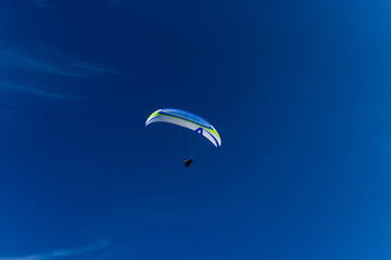 Paragliding in blue sky. Parachute with paraglider is flying. Extreme sports, freedom concept