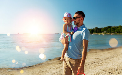 family, fatherhood and leisure concept - happy smiling father with little daughter on beach