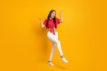 Full length photo of charming sweet young lady wear red shirt dancing rising hands arms isolated yellow color background