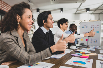 Business men and women of different nationalities give thumbs up happily and smiling. In the meeting room at the office. Concept diversity meeting happy smilling.