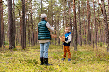 picking season, leisure and people concept - grandmother with smartphone photographing happy smiling grandson with mushrooms in basket in forest