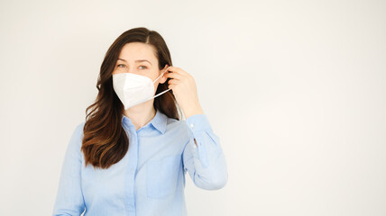 oung woman wants to put on a ffp2 protective mask. Cheerful business woman or teacher shows her ffp2 protective mask. Wearing mask in office. Person takes off the protective mask