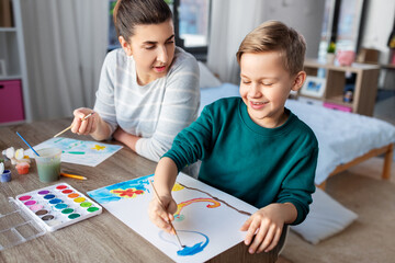 family, leisure and people concept - mother and little son with colors and paper drawing at home