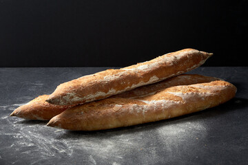 food, baking and cooking concept - pile of baguette bread on table over dark background