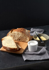 food, baking and cooking concept - close up of bread, butter in bowl, table knife and salt in cup on towel