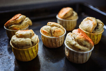 A vintage styled low-key photo of peanut butter chocolate muffins on the old used baking sheet. Soft, selective focus.