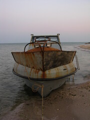 Stara zardzewiała łódź na brzegu morza wieczorem