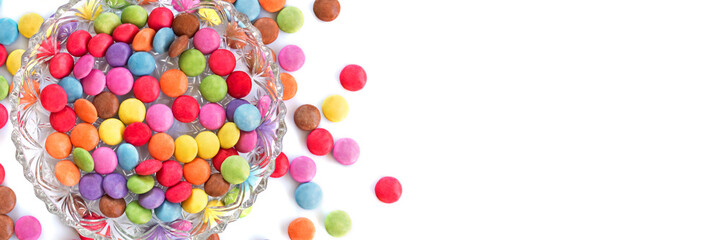 Fototapeta na wymiar Colored round candies in a plate on white background. Kid party panoramic web banner