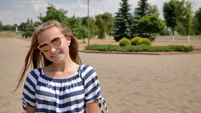 A young teenager girl poses in a summer day in a striped dress.