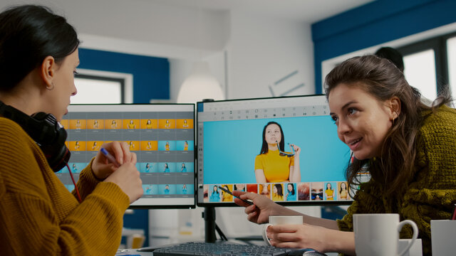 Art director teaching retoucher employee how to color gread female portret using photo editing software. Graphic designers analysing client assets from displays and taking notes in creative agency