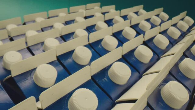 4K Row of many package with milk on blue isolated background . Dairy or juice production . Close up Shot on ARRI ALEXA Camera Laowa lens in slow motion. Closeup Dolly movement. packaging style concept