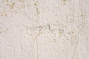 Grunge gray background of cracked peeling walls with peeled putty in beige tones.