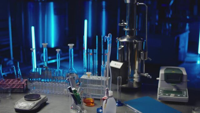 4k Medical or chemical development modern laboratory . Laboratory equipment , test tubes glasses on the table . Background with blue lights . Dark room . Shot on ARRI ALEXA camera with dolly movement 