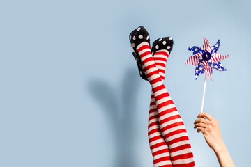 Female legs in red striped tights over blue background, focus on hand