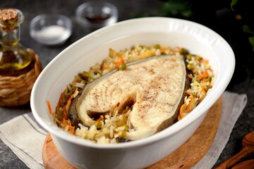 White sea fish steak with onions, carrots, green peas and rice.