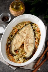 White sea fish steak with onions, carrots, green peas and rice.