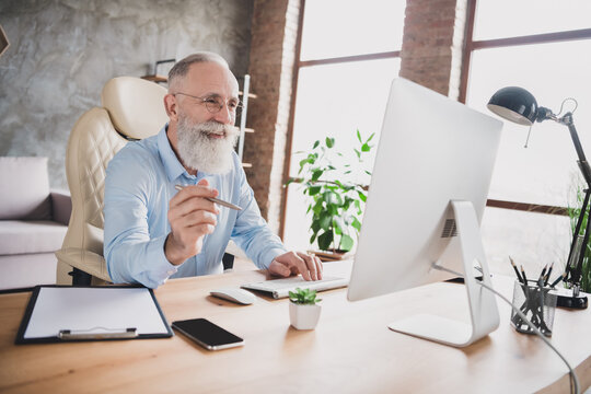 Photo of happy cheerful cool businessman old gut look computer hold pen smile indoors inside office workplace