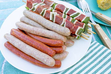 assiette de saucisses, merguez et brochettes de boeuf sur une table