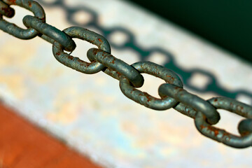 Rustic rust chain on geometric natural background, chain shadow behind, white, orange, green tones