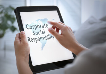 Fototapeta na wymiar Corporate social responsibility concept. Woman with tablet indoors, closeup