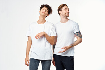 Two cheerful friends in white t-shirts emotions positive light background