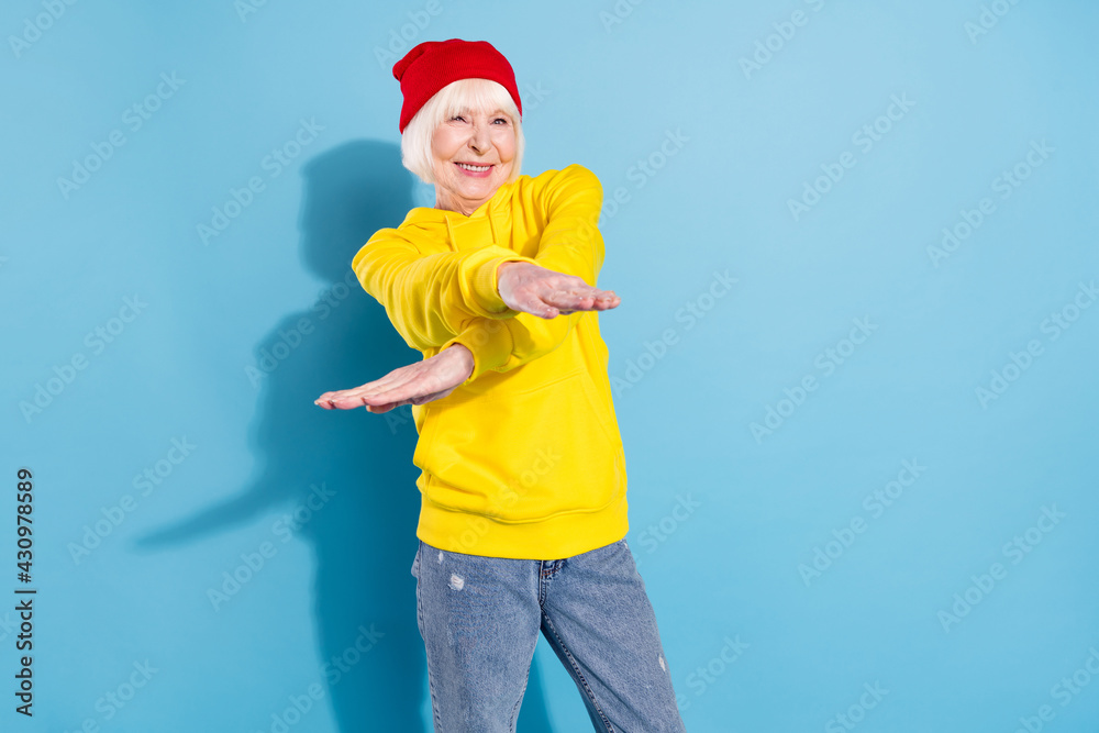 Wall mural photo of positive funky charming old woman crossed hands dance smile isolated on blue color backgrou