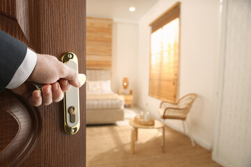 Man opening wooden door to hotel room, closeup - obrazy, fototapety, plakaty