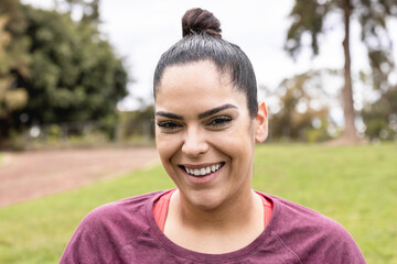 Curvy woman smiling on camera outdoors at city park after workout session - Focus on face