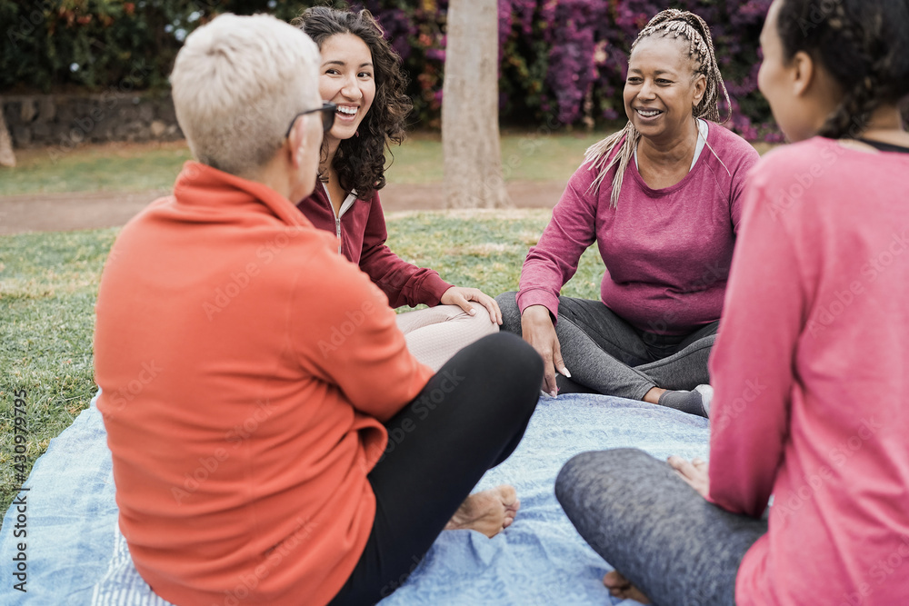 Wall mural happy multi generational women having fun together sitting outdoors at city park - focus on african 