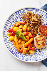 Plate with fried vegetables, carrots, broccoli, baby corn, bell peppers, roasted champignons and two chicken balls