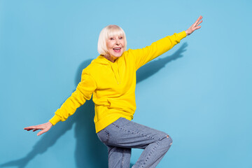 Photo of cheerful nice positive charming old woman hold hands wings plane isolated on blue color background