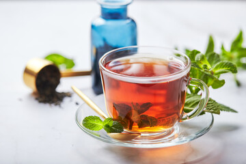 Black tea in glass transparent mug with mint leaves. Soothing tea, anti-stress