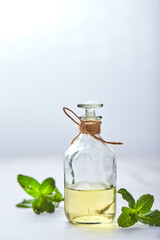 bottle with mint essential oil and green leaf on white background. Natual organic ingredients for cosmetics, skin care, body treatment. Beauty care concept