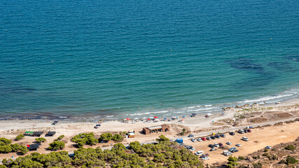 Aerial view of the Mediterranean coast with bathers and cars.