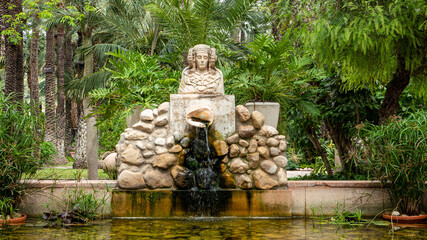 Fountain of woman bust among vegetation